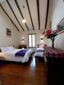 1 dormitorio con 2 camas y un jarrón de flores en Maison Fortaleza, en Cusco