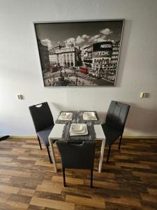 una sala da pranzo con tavolo, sedie e una foto appesa al muro di FERIENWOHNUNG APARTMENT in ZITTAUER STADTZENTRUM INNENSTADT INNENRING TOP LAGE - WOHNEN AUF ZEIT IN ZITTAU - 1 RAUM WOHNUNG a Zittau