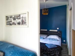 1 dormitorio con paredes azules y 1 cama con espejo en La petite Maison, en Grenoble