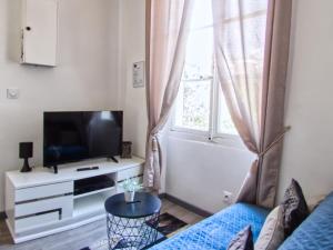 sala de estar con sofá, TV y ventana en La petite Maison, en Grenoble