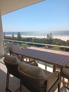 einen Tisch und Stühle auf einem Balkon mit Blick auf den Strand in der Unterkunft Kirra Surf Apartments in Gold Coast