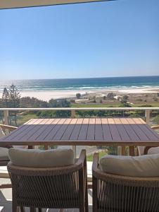 einen Tisch und Stühle auf einer Terrasse mit Blick auf den Strand in der Unterkunft Kirra Surf Apartments in Gold Coast