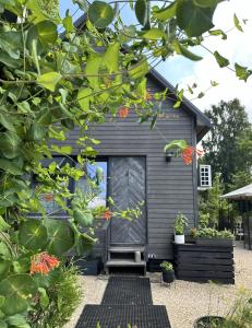 a black shed with a door and some plants at Amazing little house on an island with garden in Rīga