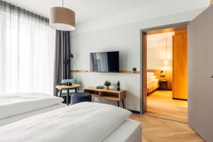 a hotel room with two beds and a tv at harry's home Graz-Smart City hotel & apartments in Graz