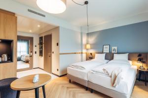 a bedroom with a large white bed and a table at harry's home Graz-Smart City hotel & apartments in Graz