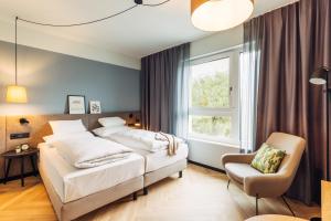 a bedroom with two beds and a chair and a window at harry's home Graz-Smart City hotel & apartments in Graz