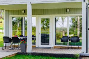 a screened porch with black chairs and a table at Namelis ant ežero kranto "Giliaus Elingas" in Tytuvėnai