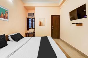 Super Hotel O Jankipuram Vikas Nagar في لاكناو: غرفة نوم بسرير وتلفزيون بشاشة مسطحة