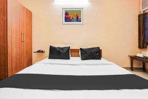 Super Hotel O Jankipuram Vikas Nagar في لاكناو: غرفة نوم بسرير ووسادتين سوداوين