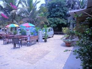 a patio with tables and chairs and umbrellas at Colva beach Xaviers Guest House in Colva