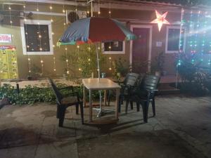 a table and chairs with an umbrella in front of a house at Colva beach Xaviers Guest House in Colva