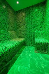 a green room with green tiled walls and benches at Family Hotel Relaxa in Sapareva Banya