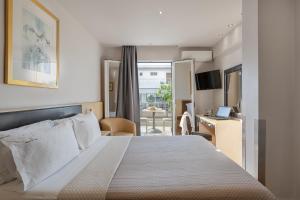 um quarto de hotel com uma cama grande e uma secretária em Piraeus City Hotel em Pireu