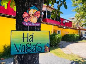 un cartel en un árbol delante de un edificio en Pousada Flor de Merepe, en Porto de Galinhas