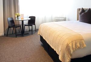 a bedroom with a bed and a table and chairs at Sudima Queenstown Five Mile in Queenstown