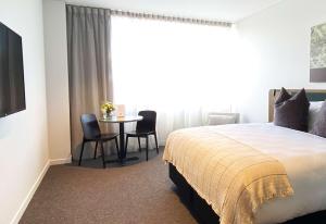 a bedroom with a bed and a table and chairs at Sudima Queenstown Five Mile in Queenstown