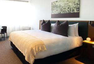 a bedroom with a large white bed with pillows at Sudima Queenstown Five Mile in Queenstown