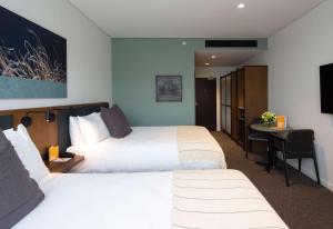 a hotel room with two beds and a desk at Sudima Queenstown Five Mile in Queenstown