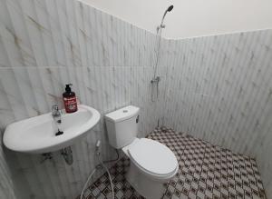 ein Badezimmer mit einem weißen WC und einem Waschbecken in der Unterkunft OYO 93306 Homestay Permana Supadio Airport in Pontianak