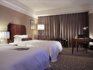 Grand New Century Hotel Binhai Tianjin في Binhai: غرفه فندقيه سريرين وبيانو