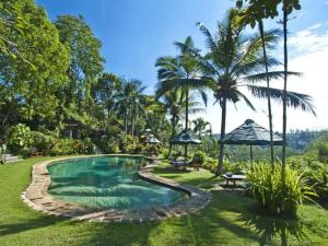 uma piscina num quintal com palmeiras em Alam Sari Keliki Resort & Spa em Ubud