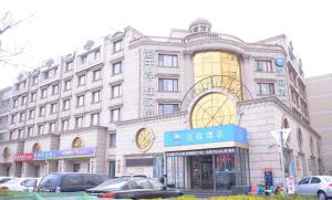 un gran edificio con coches estacionados frente a él en Hanting Hotel Tianjin Tanggu Foreign Commodities Market, en Binhai