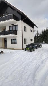 een groep sneeuwscooters geparkeerd voor een gebouw bij Aqualina Colibita in Colibiţa