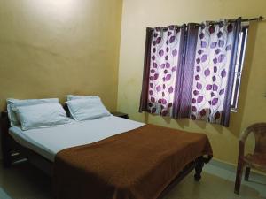 een slaapkamer met een bed en een raam met een gordijn bij Preeti villa in Madikeri