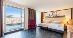 a hotel room with a bed and a red chair at PLAZA Premium Columbus Bremen in Bremen