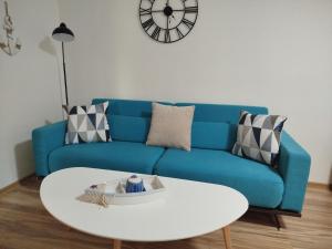 a blue couch with a white coffee table and a clock at Krásny apartmán v centre Rožňavy in Rožňava