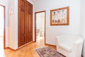 a living room with a white chair and a mirror at Tavira Casa Jenny in Tavira