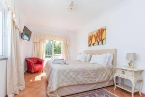 a bedroom with a bed and a red chair at Tavira Casa Jenny in Tavira