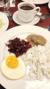 einen Teller mit Reis, ein Ei und eine Tasse Kaffee in der Unterkunft Hotel Elizabeth Cebu in Cebu City