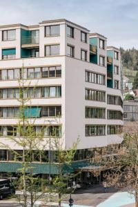 un edificio alto y blanco con árboles delante en The Yarn, en Horgen