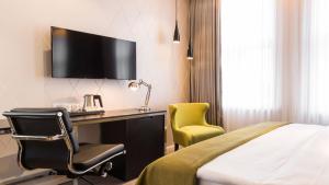 Holiday Inn Dresden - Am Zwinger, an IHG Hotel في درسدن: غرفة في الفندق بها سرير ومكتب وتلفزيون