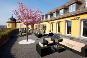 une terrasse avec des canapés et un arbre en face d'un bâtiment dans l'établissement Hotel Schloss Montabaur, à Montabaur