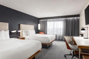 Courtyard Houston Sugar Land/Stafford في ستافورد: غرفة فندقية بسريرين ومكتب