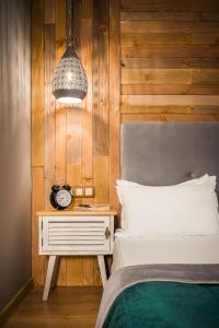 - une chambre avec un lit et une table de chevet avec une horloge dans l'établissement Mоura Boutique & SPA Hotel Borovets, à Borovets