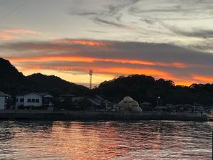 a sunset over a body of water with houses at 一日限定一組の宿なんでもん in Naoshima