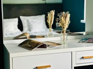 a white dresser with two vases and a mirror at Apartamenty A&M in Stargard