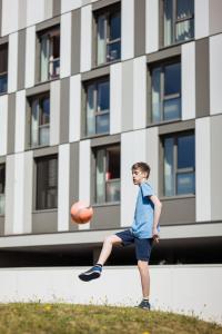 Ein kleiner Junge mit einem Basketball vor einem Gebäude. in der Unterkunft Premiere Classe Le Havre Centre-LES DOCKS in Le Havre