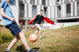 Zwei Männer spielen mit einem Ball auf einem Feld mit Sonnenschirmen in der Unterkunft Premiere Classe Le Havre Centre-LES DOCKS in Le Havre