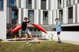 Zwei Jungs spielen mit einem Fußball auf einem Feld in der Unterkunft Premiere Classe Le Havre Centre-LES DOCKS in Le Havre