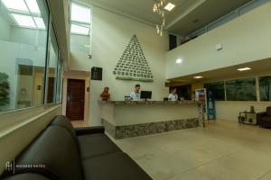 a lobby with two people at a counter with a christmas tree at Rede Andrade Solmar in João Pessoa