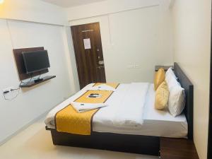 um quarto com uma cama e uma televisão na parede em Habitat Inn em Pune