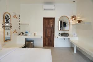 een witte kamer met een houten deur en een wastafel bij El Tropico Boutique Hotel in Kuta Lombok