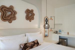 een slaapkamer met een bed met witte kussens en decoraties bij El Tropico Boutique Hotel in Kuta Lombok