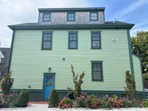 a green house with a blue door and flowers at 10 Fair H in Newport