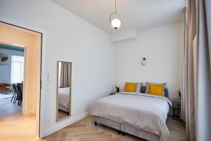 ein Schlafzimmer mit einem Bett mit gelben Kissen und einem Spiegel in der Unterkunft Urban Chic Apartment in the Heart of Mechelen in Mechelen