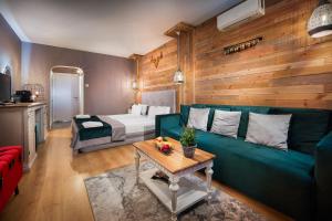 - un salon avec un canapé vert et un lit dans l'établissement Mоura Boutique & SPA Hotel Borovets, à Borovets